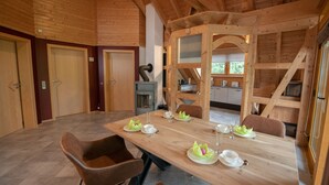 A wooden dining room with a long table set for four, including plates, glasses, and cutlery.