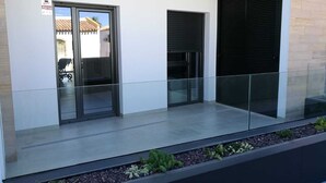 Een modern gebouw met een glazen balkon, een schuifdeur en een raam met een zwart luik.