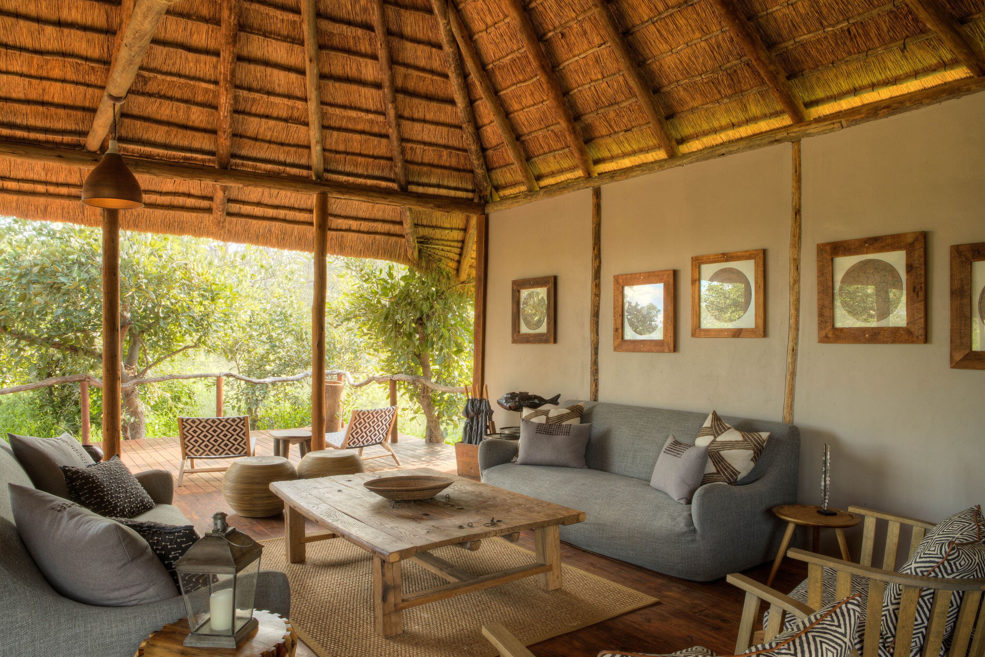 A cozy living area with a thatched roof, a sofa, a coffee table, and framed pictures on the wall.