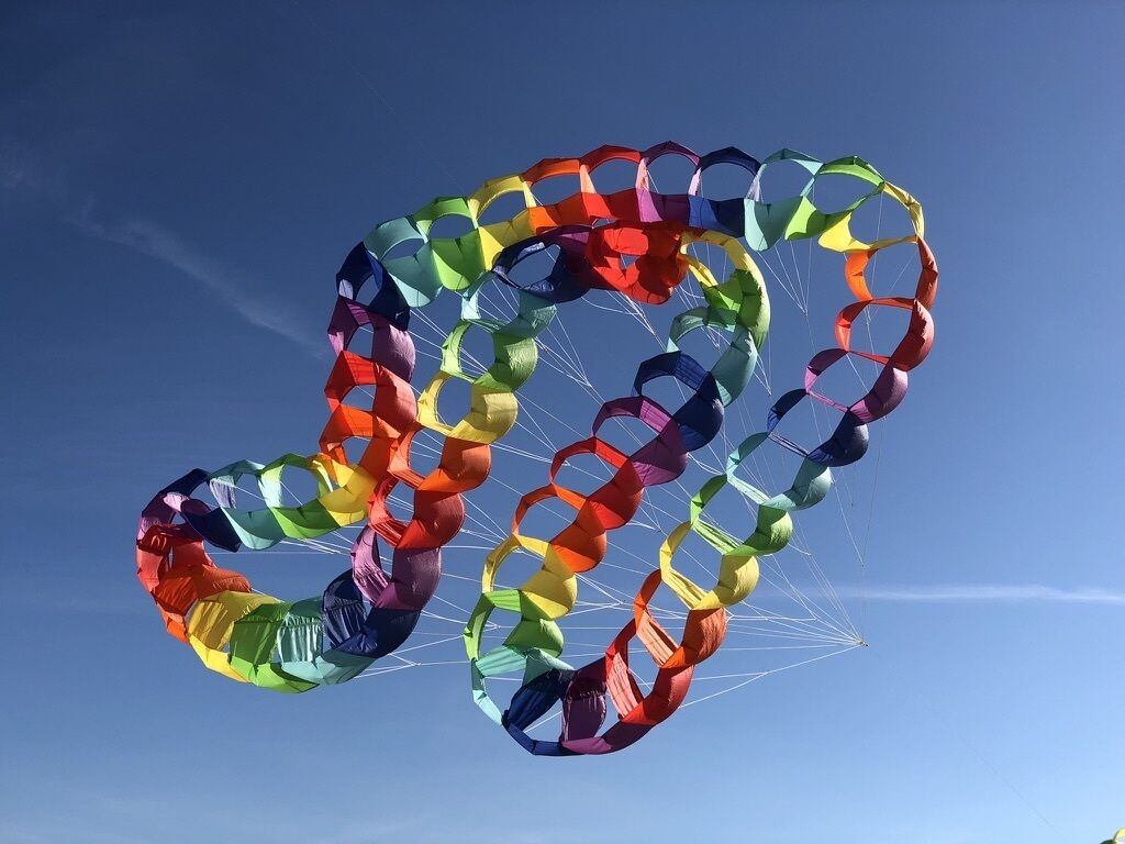 Eine farbenfrohe, fallschirmartige Struktur vor blauem Himmel.