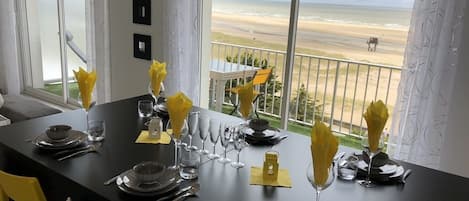 A dining table set for four with a view of the beach.