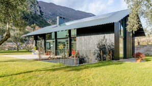 A modern house with a large glass facade, a metal roof, and a well-maintained lawn. - A tranquil paradise overlooking the lake (Arco)