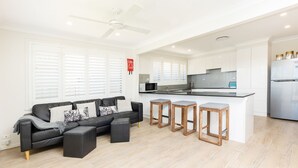 Una cocina moderna con armarios blancos, un refrigerador de acero inoxidable y una encimera negra.