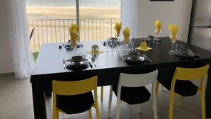 A dining table set for four with a view of the beach.