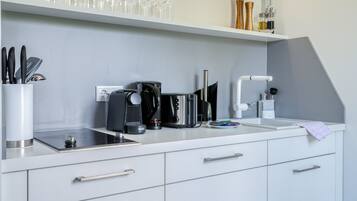 Et moderne køkken med en hvid bordplade, kaffemaskine og en neonskilte over.