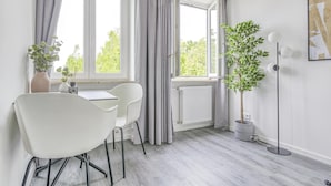 Ein modernes Zimmer mit Esstisch, Stühlen, einer Topfpflanze und einer Stehlampe.