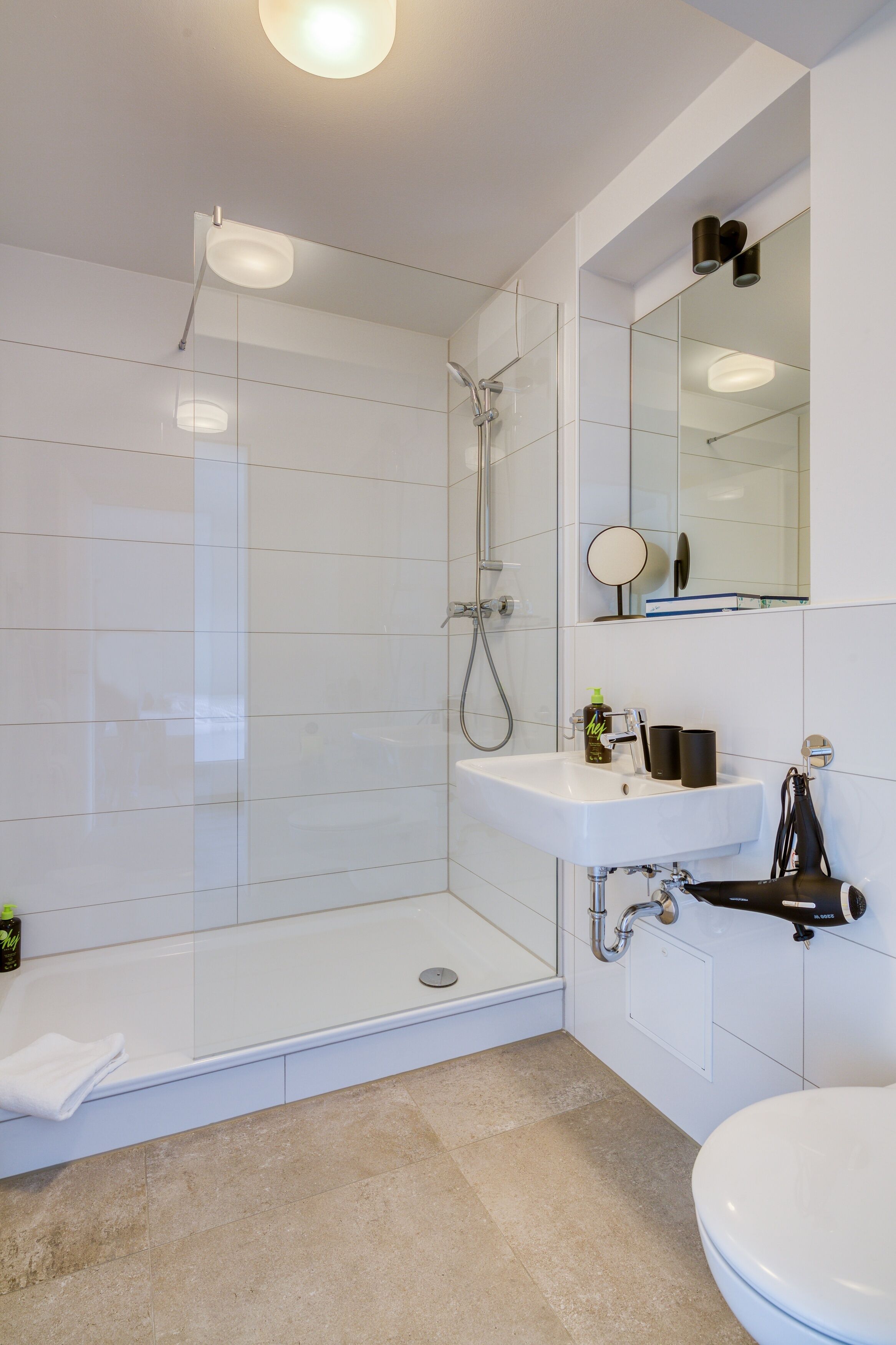 A modern bathroom with a glass-enclosed shower, a white sink, and a toilet.