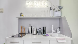 Eine moderne Küche mit einem 'go suite'-Schild, einer Kaffeemaschine, einem Wasserkocher und verschiedenen Küchenutensilien auf der Arbeitsfläche.