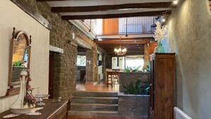 A spacious hallway with stone walls, wooden beams, and a staircase leading to a second floor. - CAL SERRA-Rural house (Alentorn)