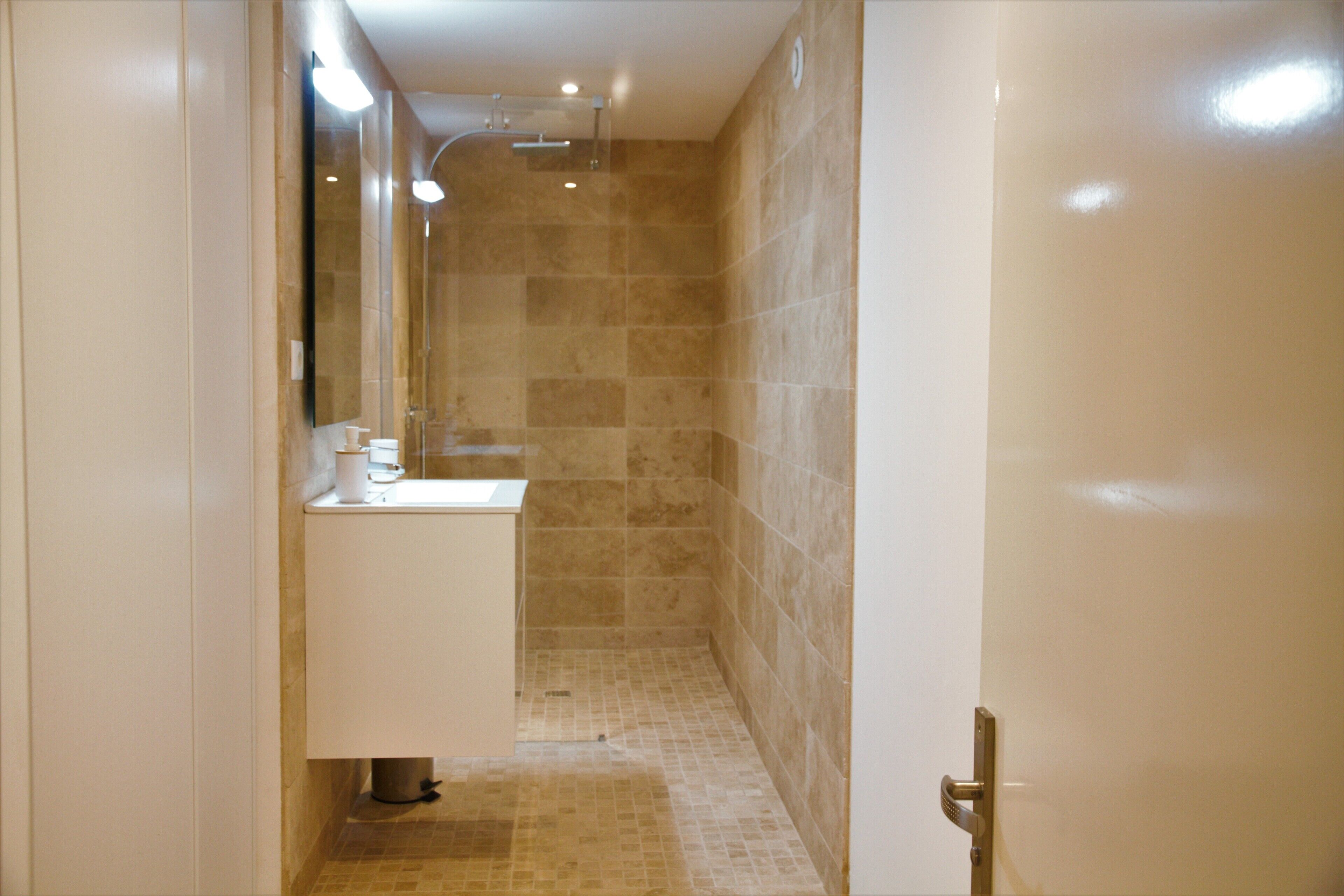 Une salle de bain équipée d’un lavabo, d’un miroir et d’un espace douche.