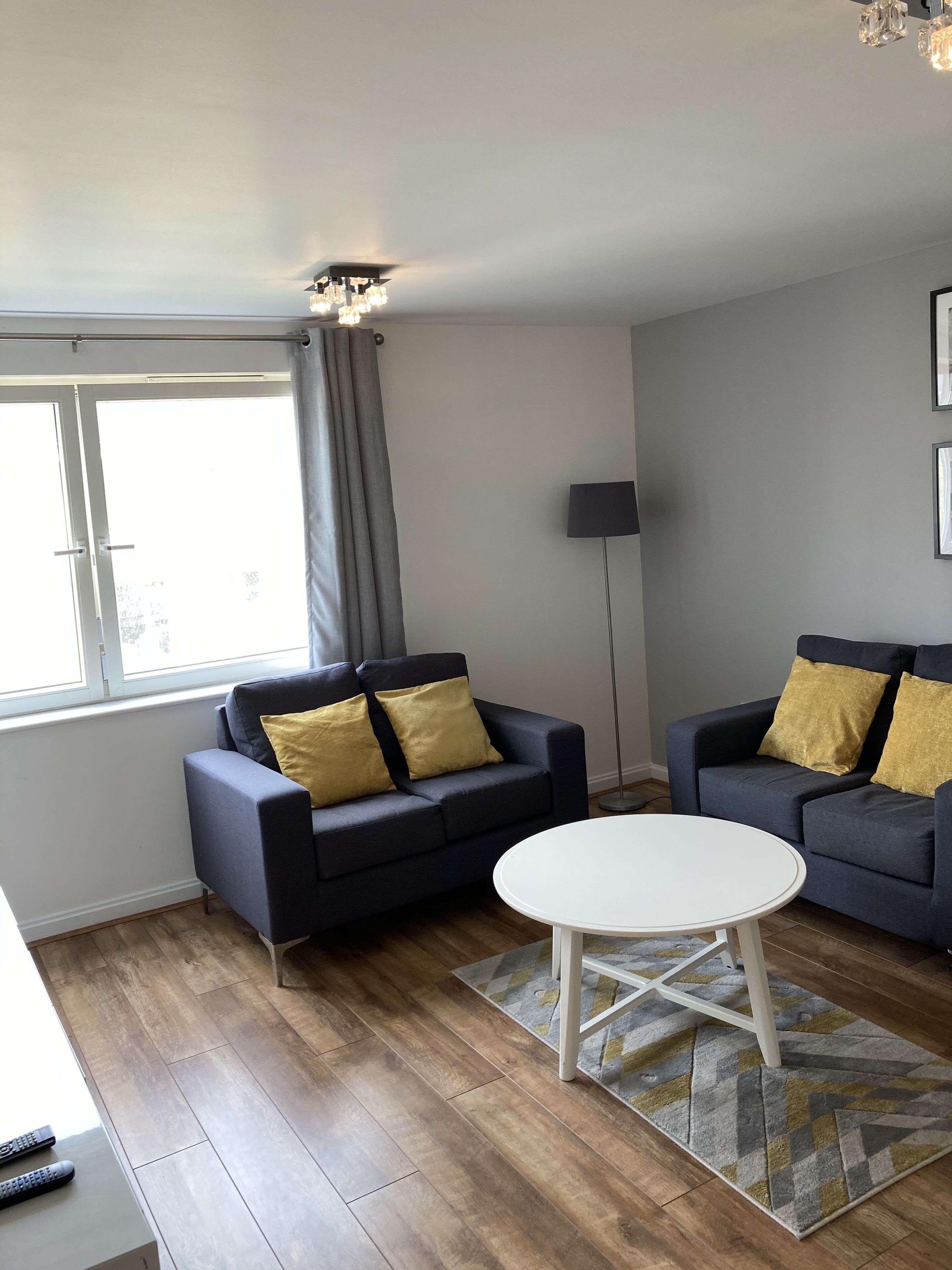 Ein modernes Wohnzimmer mit zwei dunklen Sofas, einem weißen Couchtisch und einem gemusterten Teppich.