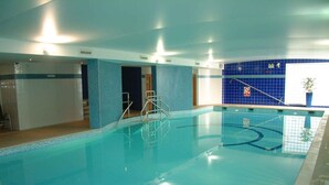 An indoor swimming pool with clear water, tiled walls, and a blue accent wall.