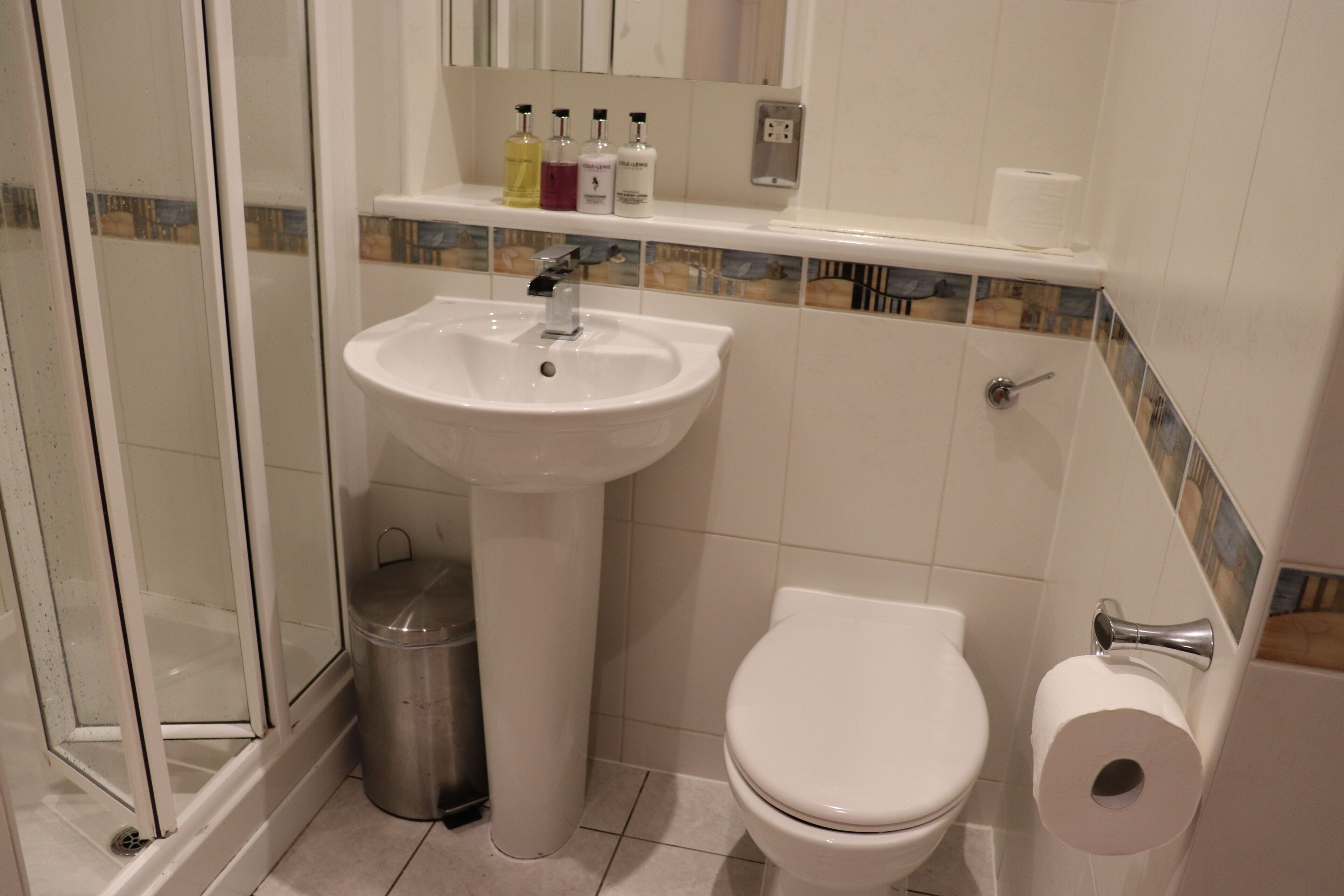 Un baño con lavamanos blanco, inodoro y cabina de ducha de vidrio.