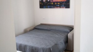 A bedroom with a bed, a door, and a cityscape painting on the wall. - Quiet room in new apartment (Verona)