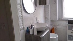 A modern bathroom with a large mirror, a sink, a toilet, and a cabinet. - Quiet room in new apartment (Verona)