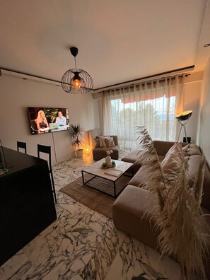 A modern living room with a sofa, coffee table, and TV. - Sunny terrace apartment with sea view (Nice)