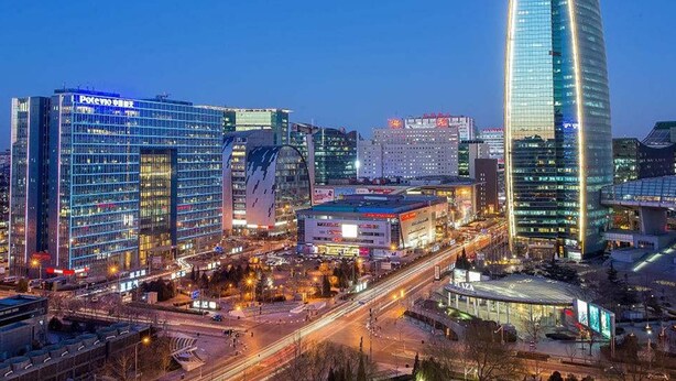 A cityscape with modern high-rise buildings, including a prominent curved skyscraper. - James Joyce Coffetel (Beijing)