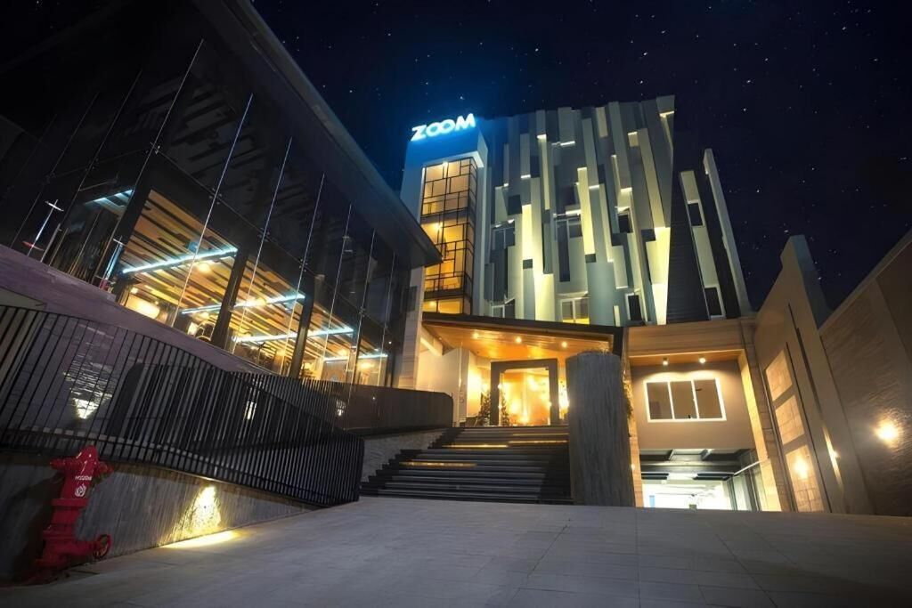 A modern building with a 'ZOOM' sign, a staircase leading to the entrance, and a fire hydrant on the left.