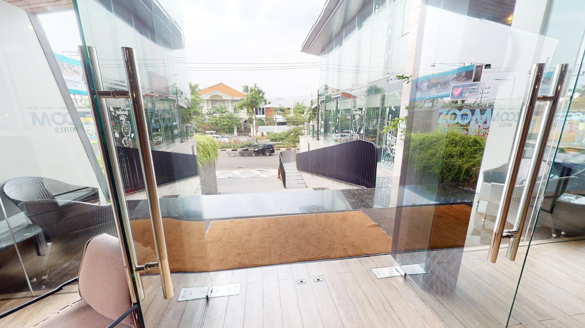 A modern hotel room with a glass door leading to a courtyard, a small rug, and a chair.