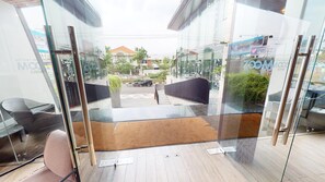 Habitació d'hotel moderna amb una porta de vidre que dóna a un pati interior, una catifa petita i una cadira.