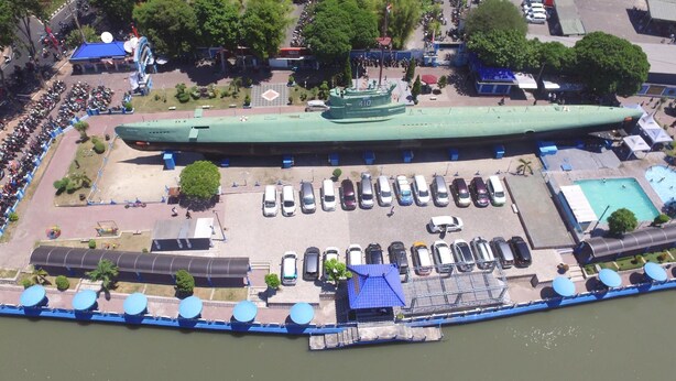 Um edifício grande em formato de barco, com estacionamento e um cais.
