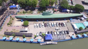 Un barco verde grande amarrado en un puerto deportivo, con un estacionamiento y una pequeña zona de piscina.