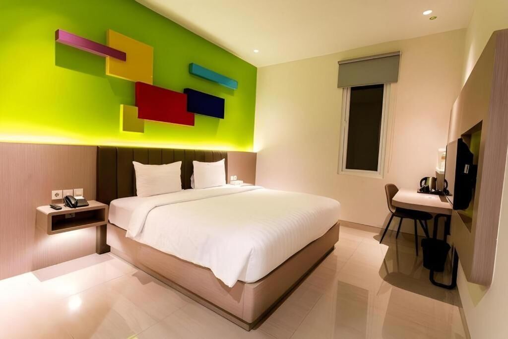 A modern hotel room with a large bed, bedside tables, a desk with a chair, and a TV.