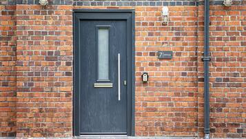 A dark-colored door with a vertical handle and a small rectangular window.