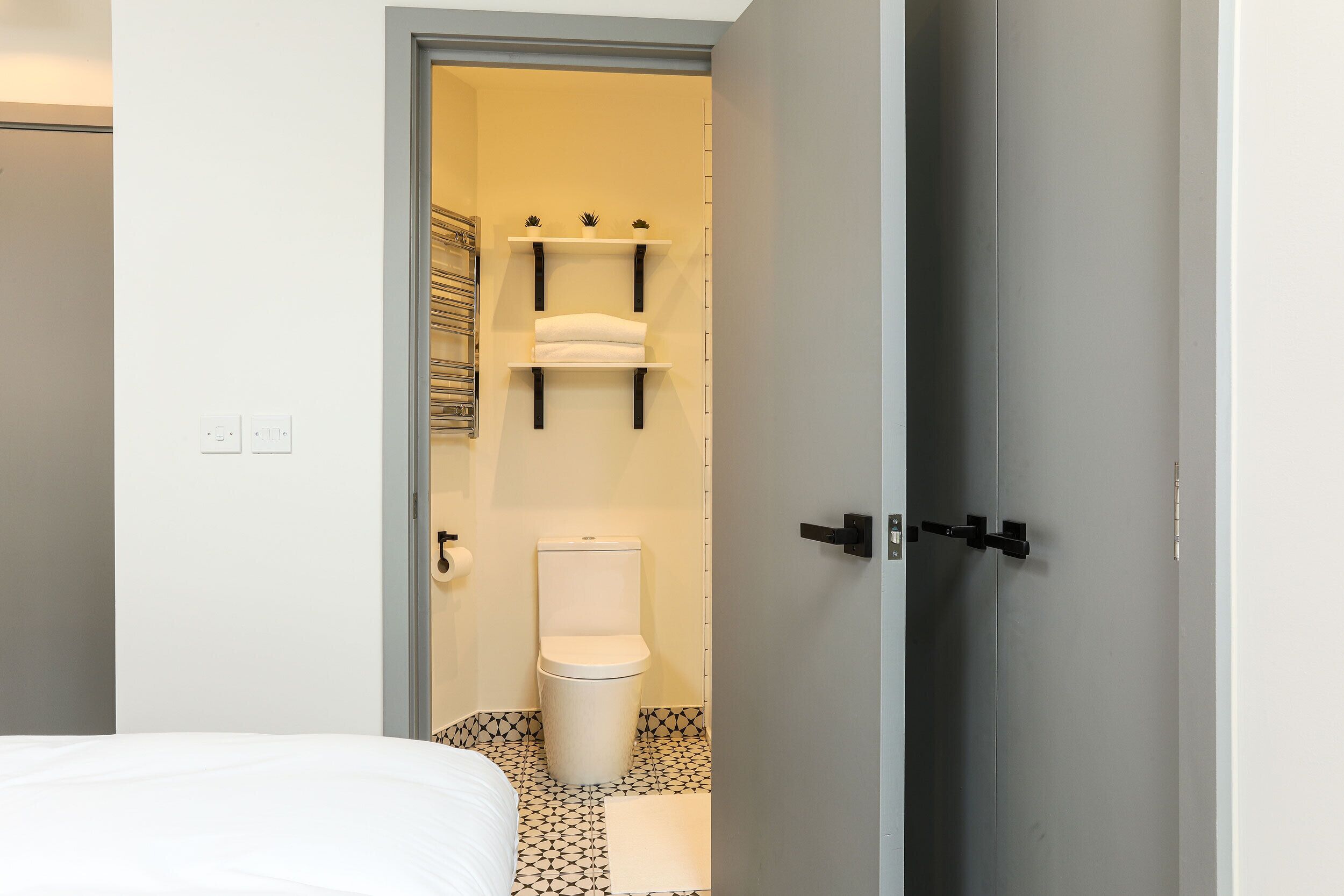 A modern bathroom with a toilet, towel racks, and a shower area.