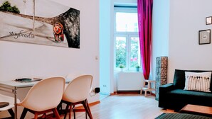 A modern living room with a dining area, a black sofa, a wooden coffee table, and a painting on the wall. - Quiet studio in Prenzlauer Berg near Mauerpark (Berlin)