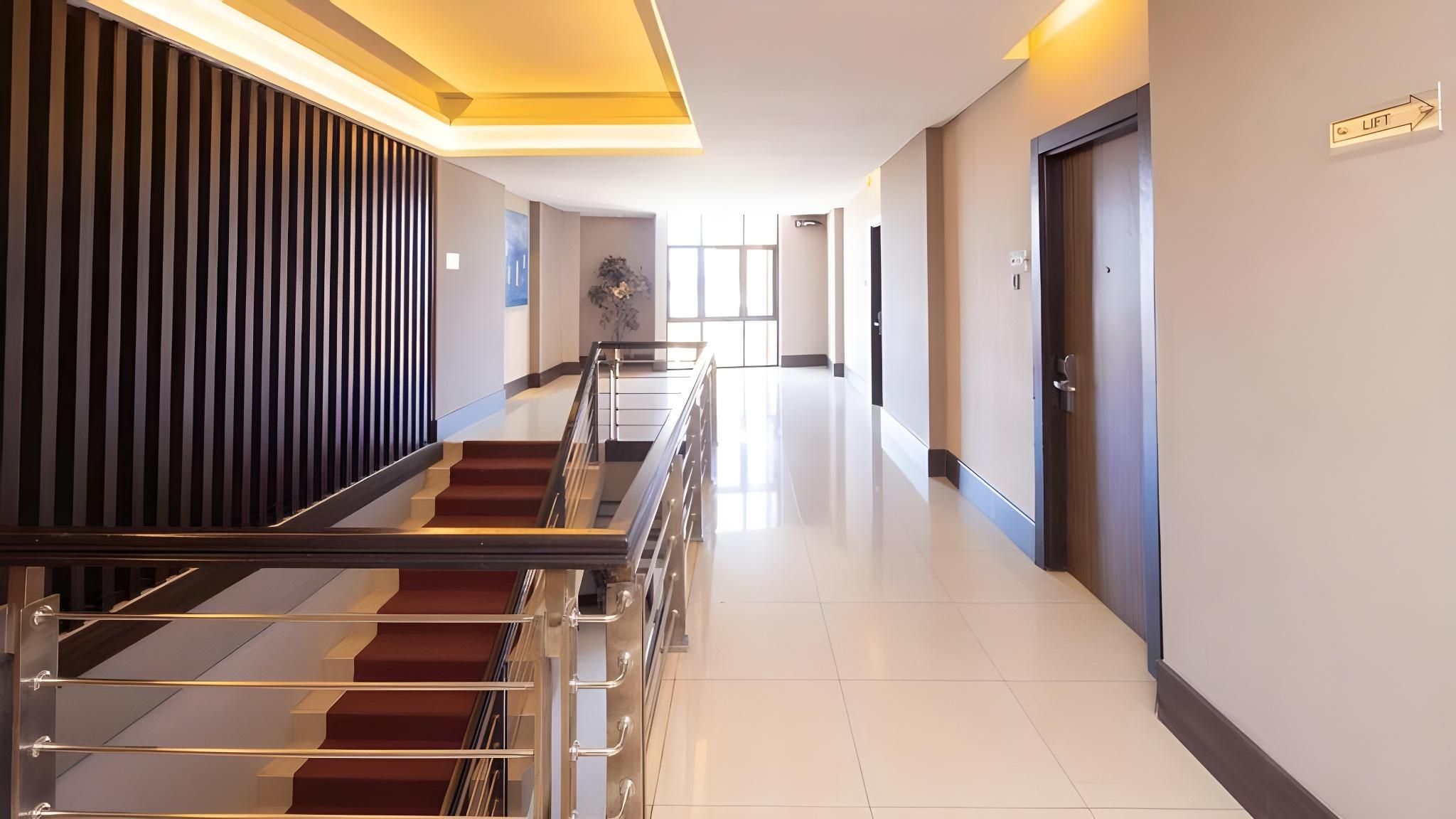 A hotel corridor with a staircase, doors, and a lift sign.
