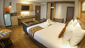 A hotel room with a bed, a desk, a television, and a kitchenette. - Diamond Hotel Samarinda (Samarinda)