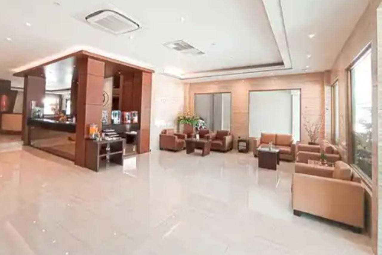 A spacious hotel lobby with a reception desk, seating area, and large windows.