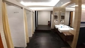A modern hotel corridor with a central staircase, a bathroom with a large mirror and sink, and a fire extinguisher on the wall. - Diamond Hotel Samarinda (Samarinda)