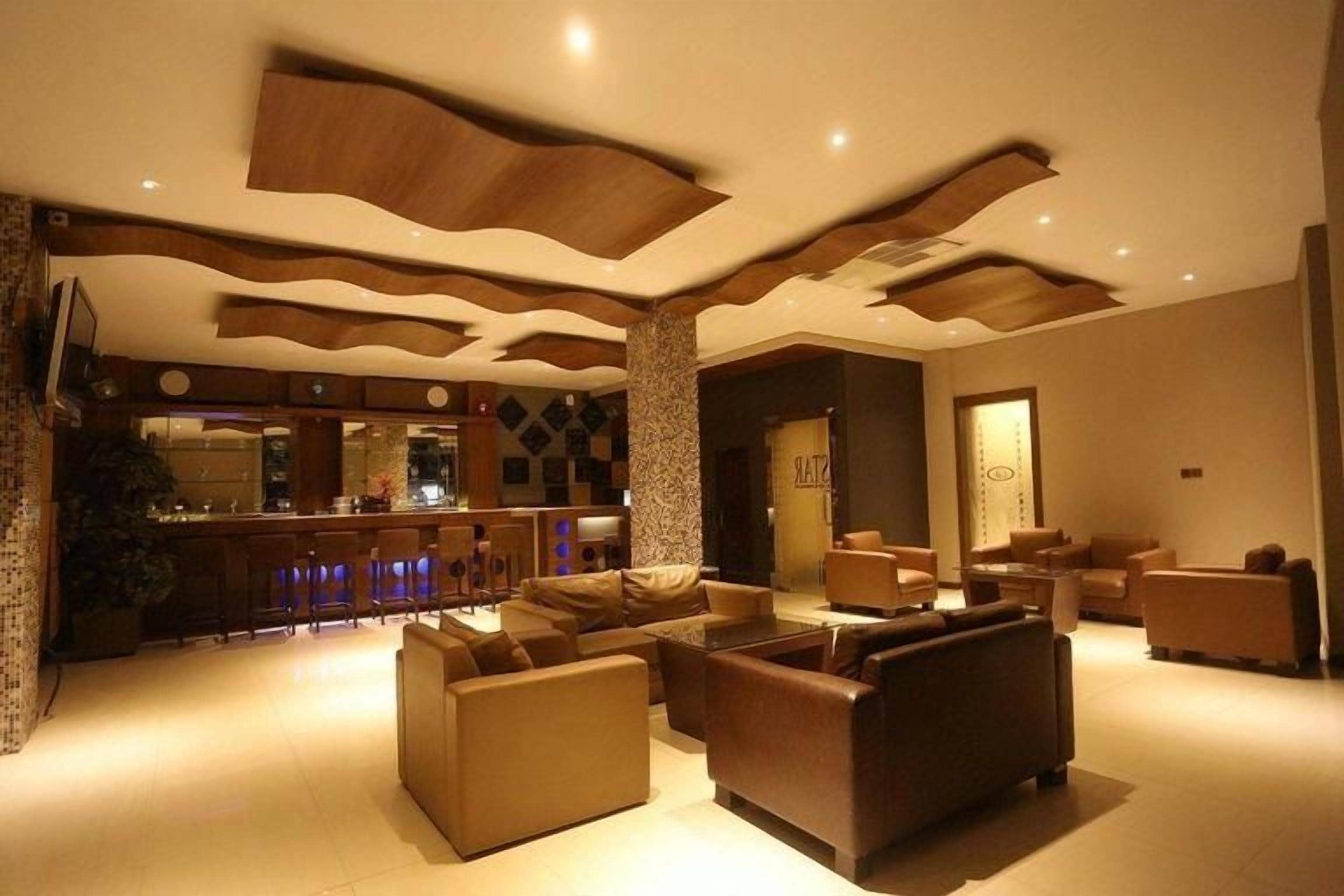 A modern living room with sofas and a bar area in the background.