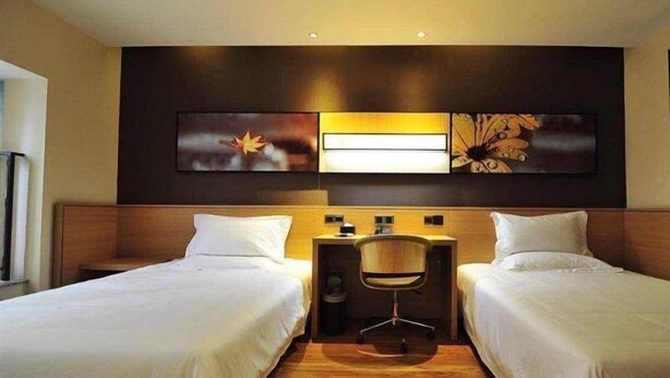 A hotel room with two single beds, a desk with a chair, and artwork on the wall. - IU Hotel Bijie Weining Caohai (Bijie)