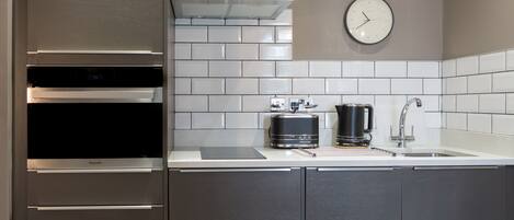 Una cocina moderna con electrodomésticos de acero inoxidable, una cafetera y un reloj en la pared.