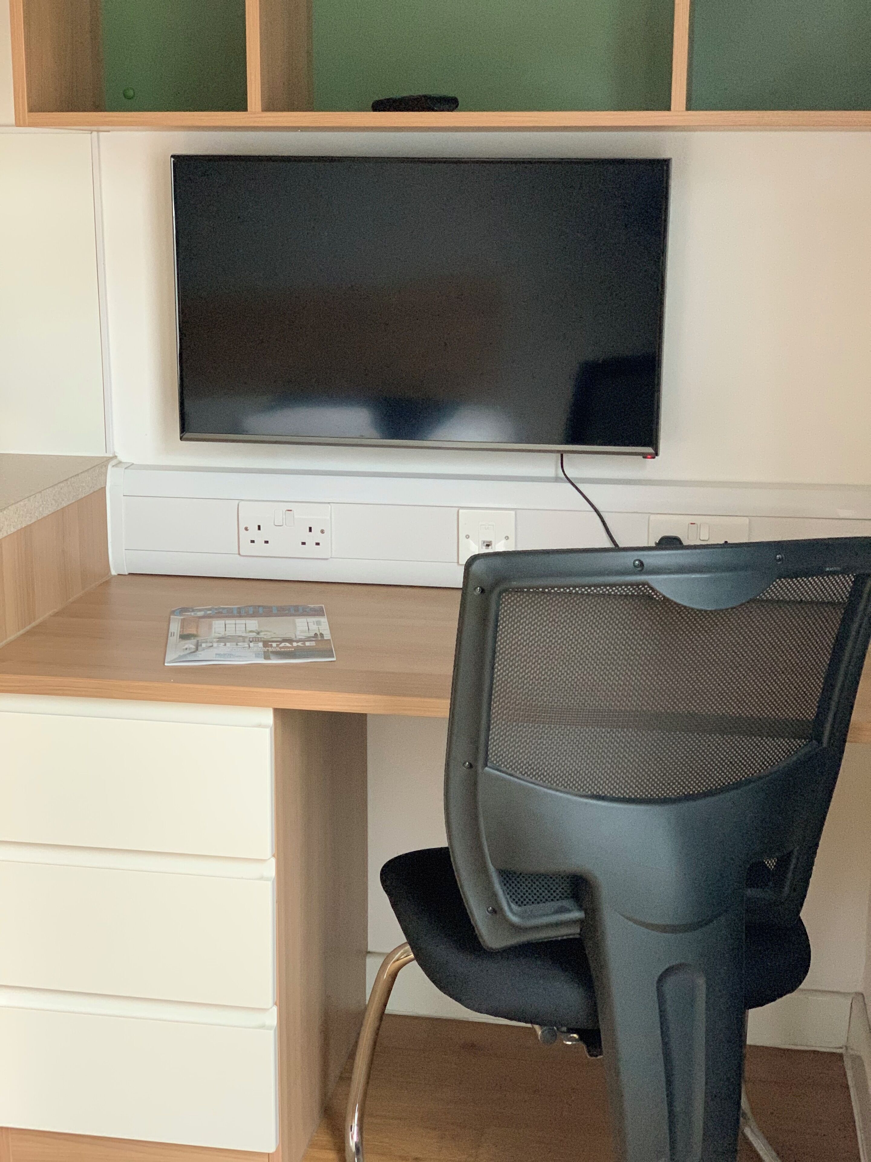 Un espace de travail comprenant un bureau, une chaise et un grand écran.