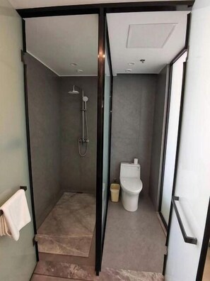 Uma casa de banho moderna com cabine de chuveiro em vidro, sanita e soalho em mármore.