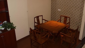 A dining area with a wooden table and chairs, a potted plant, and a shelf with items. - Greentree Inn Xuzhou West District Huohua Shell Ho (Xuzhou)