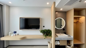 A modern bathroom with a flat-screen TV, a large mirror, a sink, and a shower area. - Greentree Inn Xuzhou West District Huohua Shell Ho (Xuzhou)