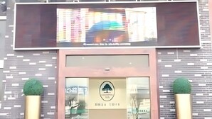 A building entrance with a glass door, a logo, and two potted plants. - Greentree Inn Xuzhou West District Huohua Shell Ho (Xuzhou)