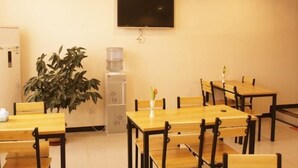 A conference room with tables and chairs, a water dispenser, a television mounted on the wall, and a potted plant. - Greentree Inn Baoding Sanfeng Road Agricultural Un (Baoding)