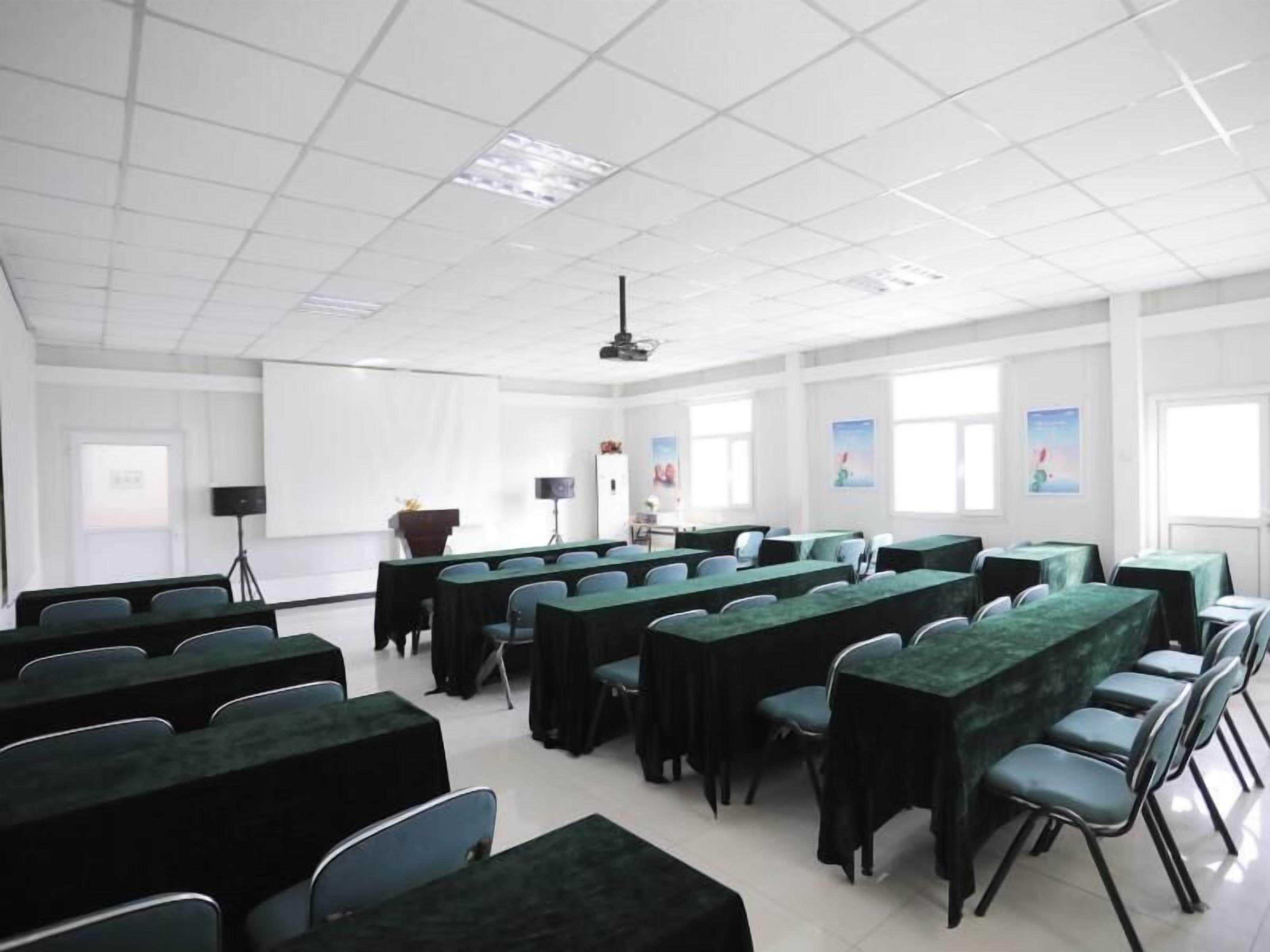 A conference room with multiple tables and chairs, a projector, and a screen.