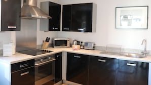 A modern kitchen with stainless steel appliances, black cabinets, and a granite countertop. - Quayside by Urban Space (Cardiff)