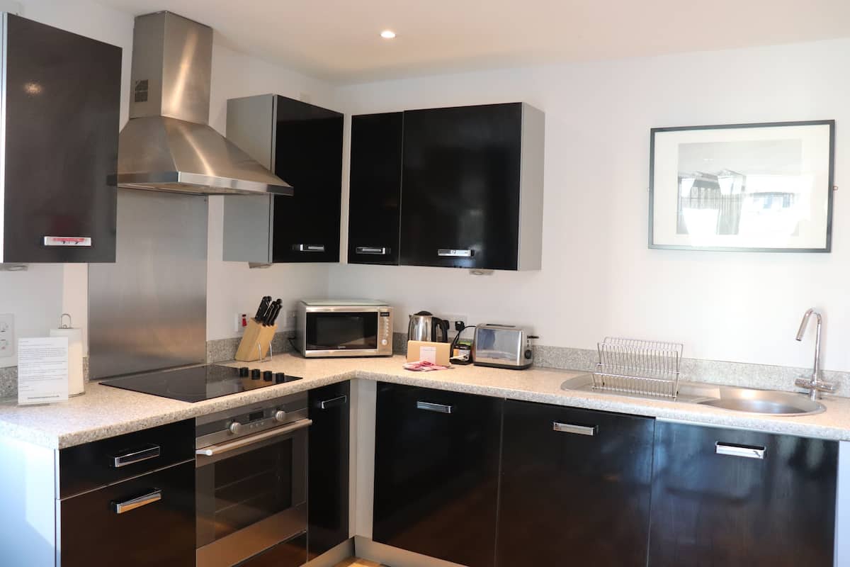 A modern kitchen with stainless steel appliances, black cabinets, and a granite countertop.