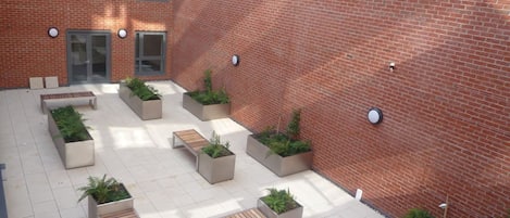 A courtyard with outdoor seating, planters, and a brick wall.