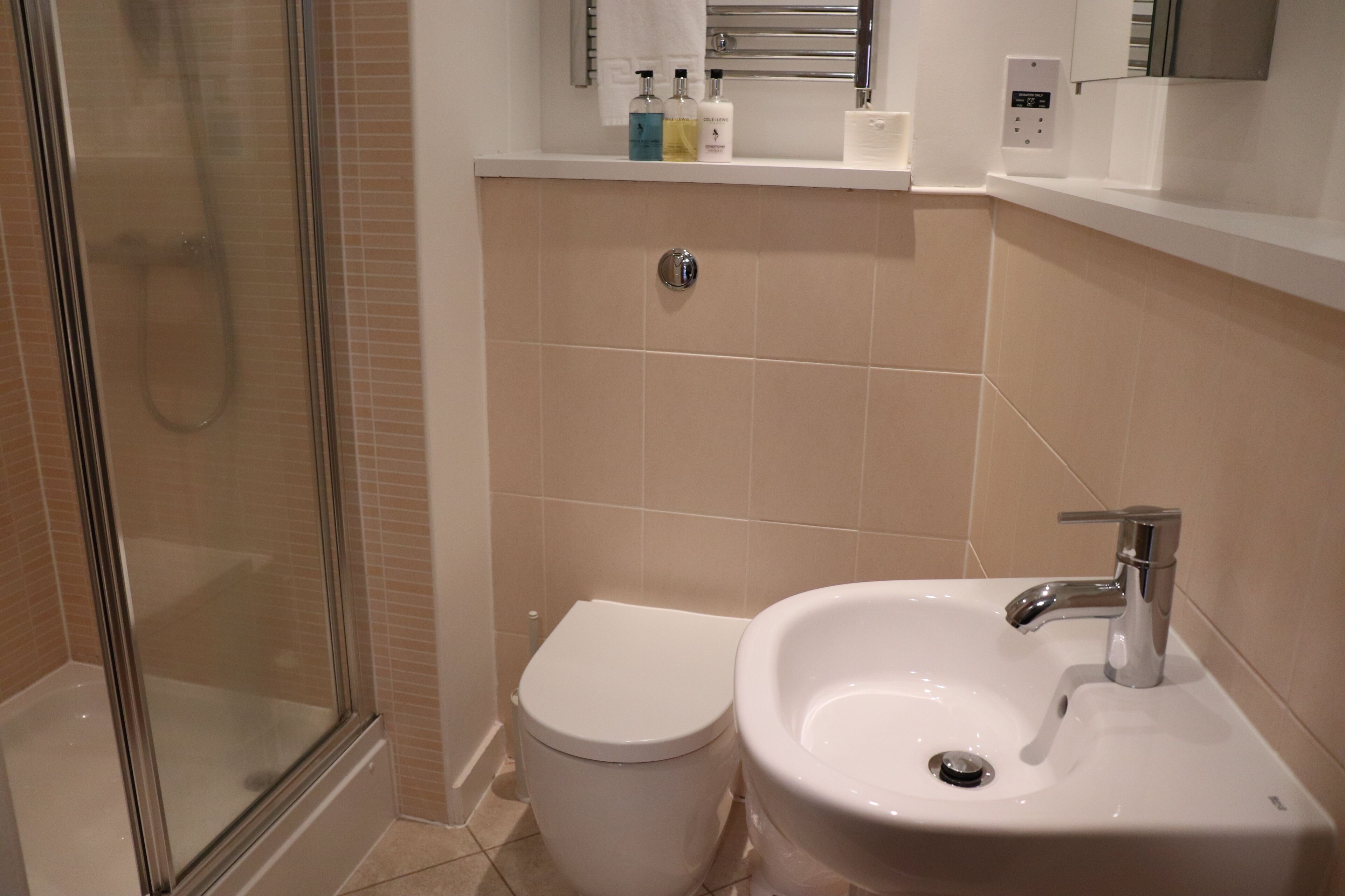 Ein Badezimmer mit einer gläsernen Duschkabine, einer weißen Toilette und einem Waschbecken mit Chromarmatur.