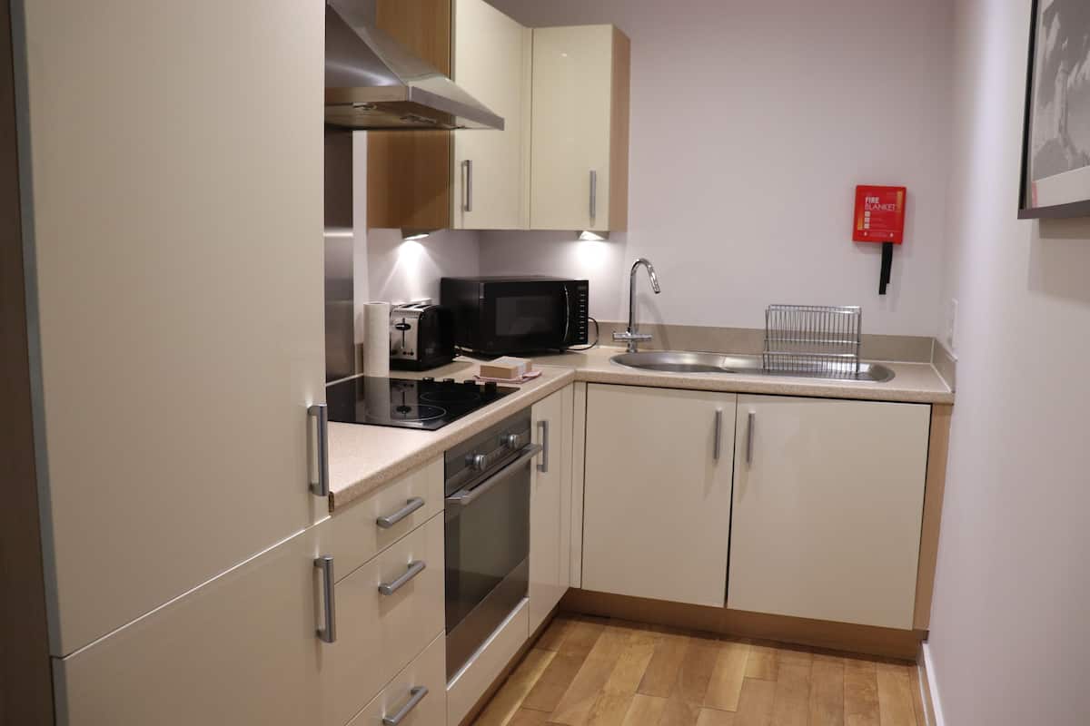A compact kitchen with a microwave, stove, sink, and cabinets.