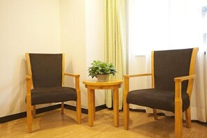 Two wooden chairs with dark cushions, a small round wooden table, and a potted plant. - Vatica Hefei Maanshan Road Lvdiyinghai Zhugang Met (Hefei)